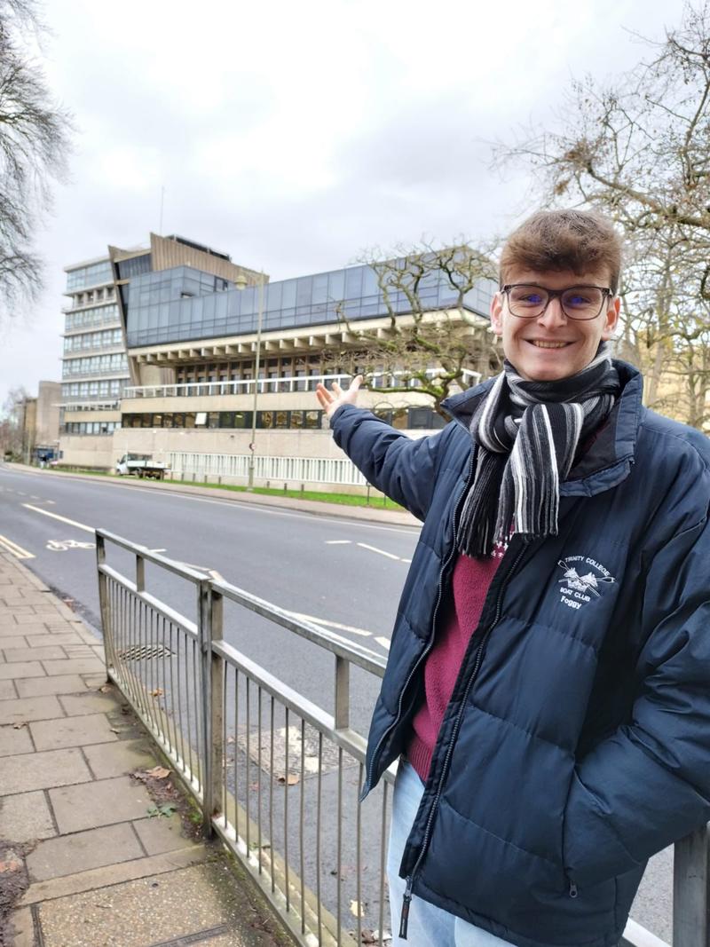 Thomas Fogg proudly pointing to the Denys Wilkinson Building where he completed his award-winning MPhys project on the innovative GaToroid particle therapy system.