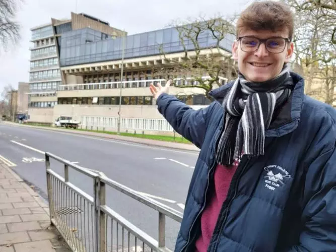 Thomas Fogg proudly pointing to the Denys Wilkinson Building where he completed his award-winning MPhys project on the innovative GaToroid particle therapy system.